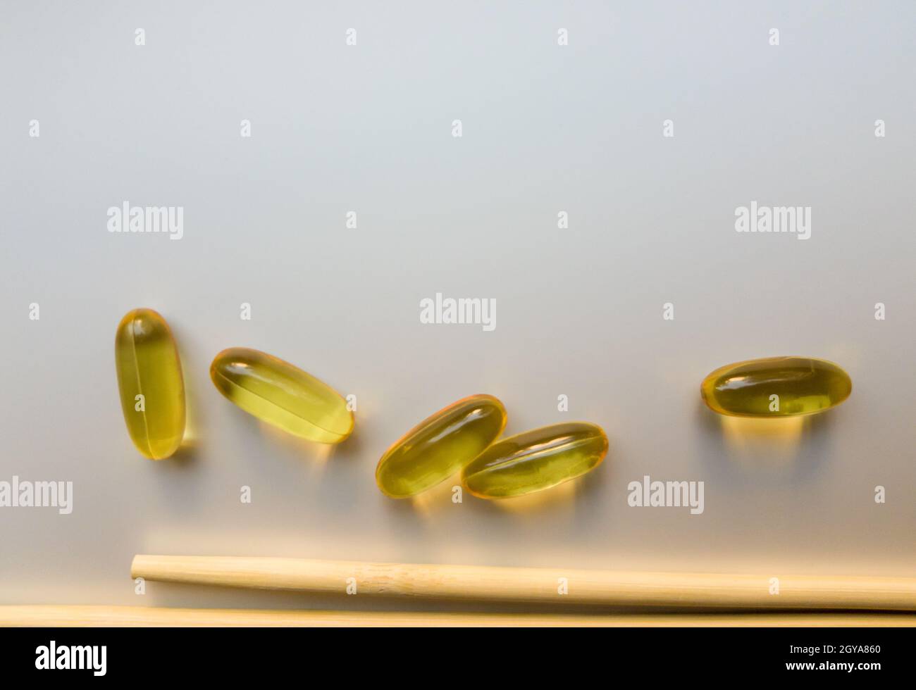 Fish oil capsules with Chinese chopsticks. Omega 3 on a white background. High Resolution Product. Food supplement. Vitamins for a healthy lifestyle. Stock Photo