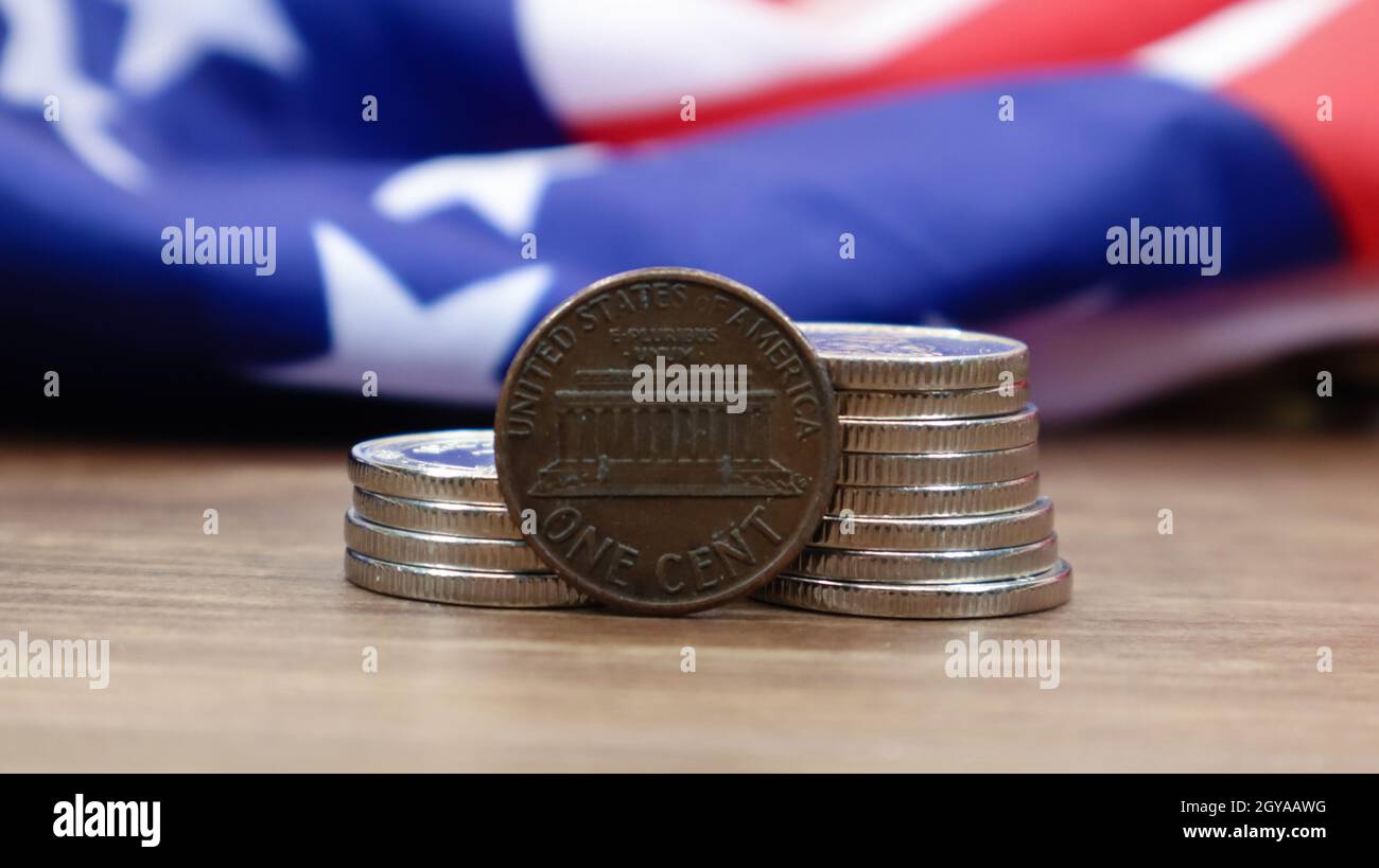 A 1 cent American dollar coin lies on the American flag. The currency is one cent over the flag of the United States Stock Photo