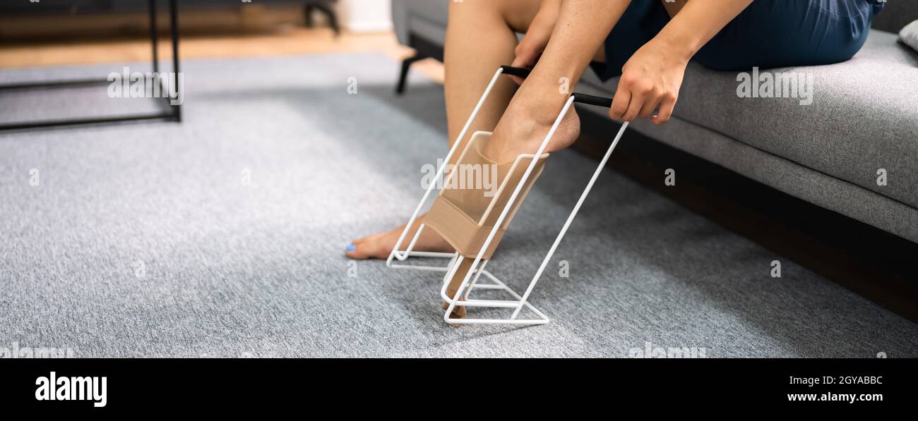 Woman Putting On Medical Compression Stockings Using Stocking Aid