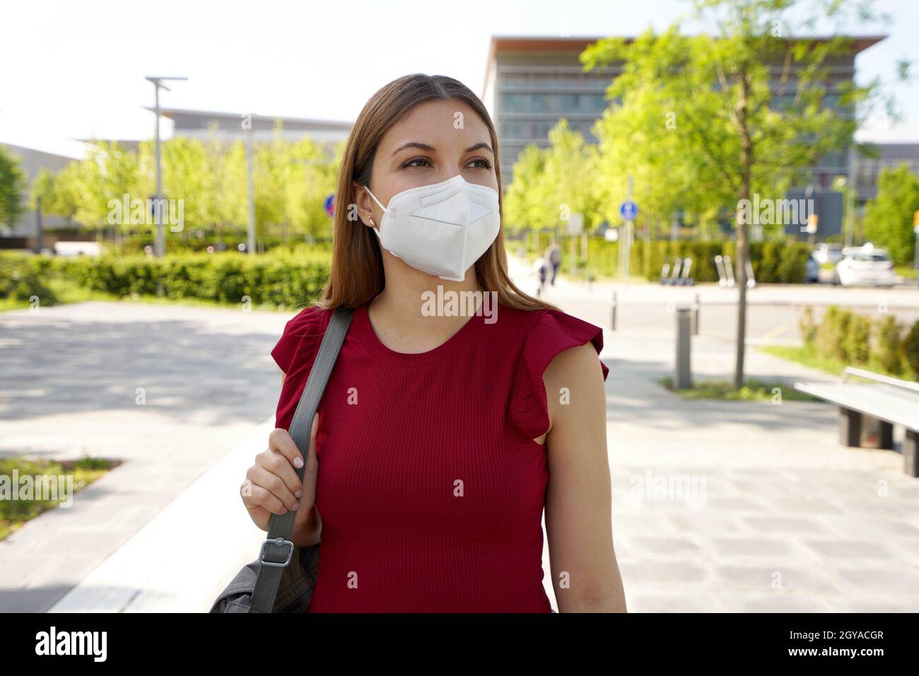 Reflective young woman in empty city street wearing protective mask ...