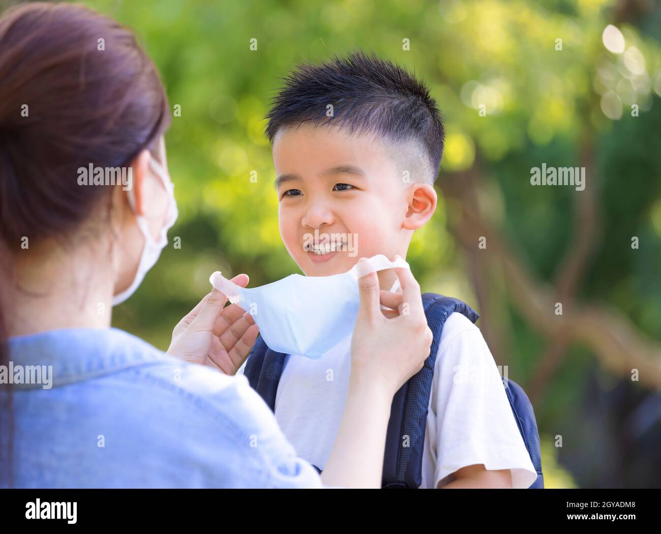 Happy Mother help son wearing medical mask at school Stock Photo