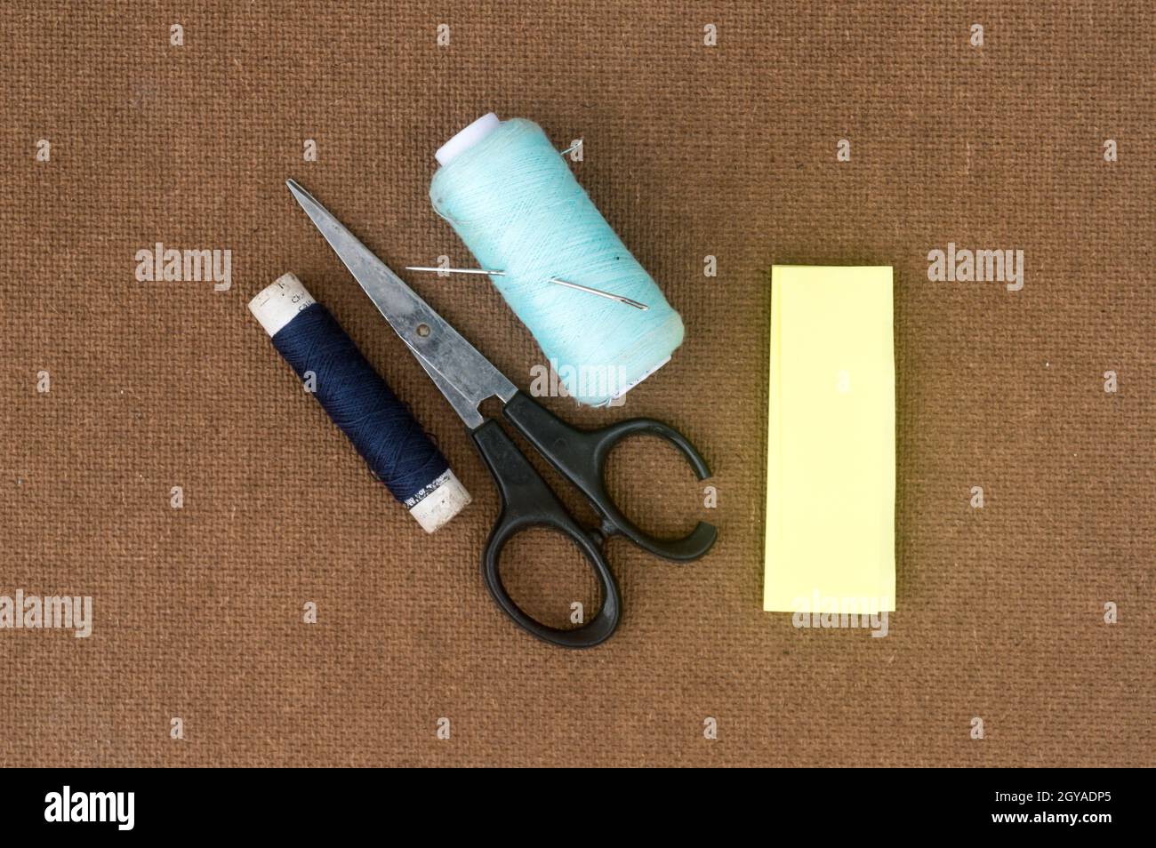 Group of sewing tools and items for knitting and weaving placed on a brown colour woven paper board. DIY Art and craft background concept. Stock Photo