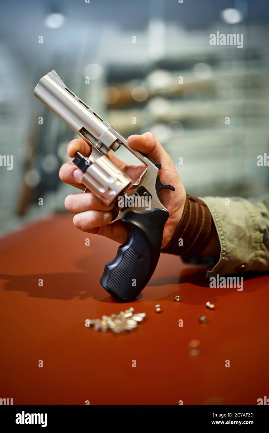 Man reload revolver at the counter in gun store. Weapon shop interior