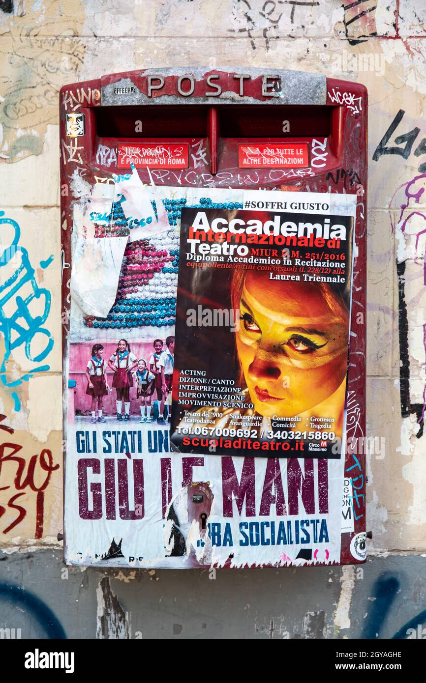 Poste Italiane letter box covered in paste-up posters in Trastevere district of Rome, Italy Stock Photo