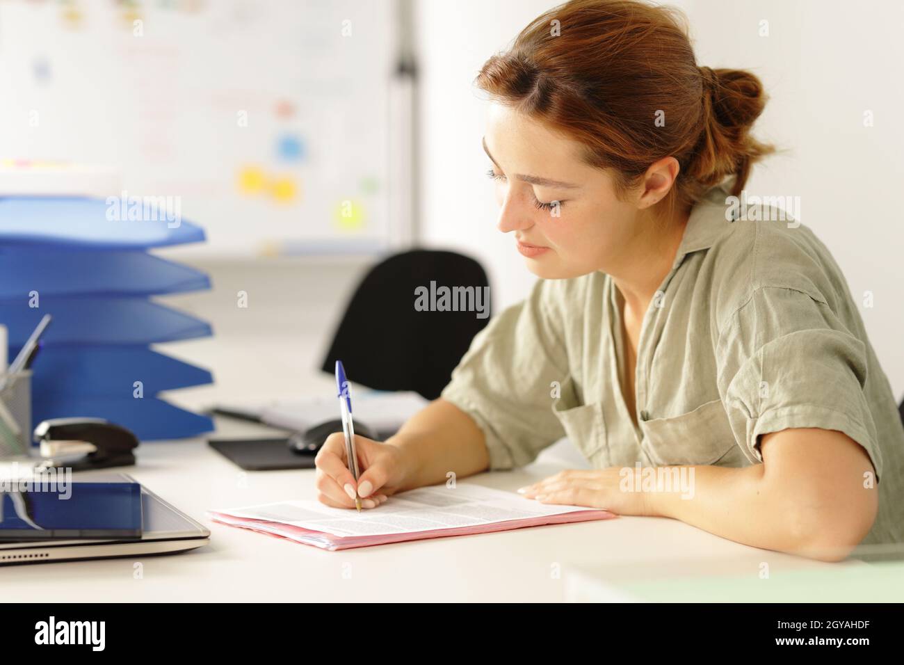 Relaxed woman working filling paper form on a desk at office Stock Photo