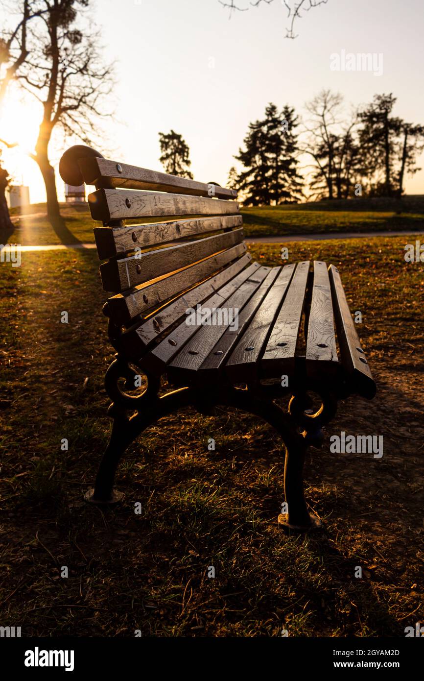 Bench at sunset in autumn at city park shined by the sun. Golden hour ...