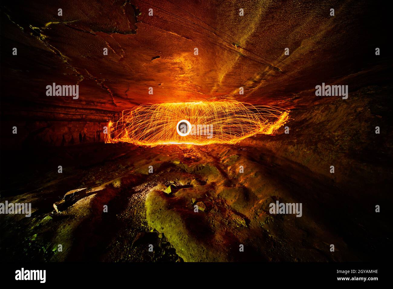 Fire dome and ring of orange sparks inside a wide but narrow cave with a smooth ceiling and a bumpy floor Stock Photo