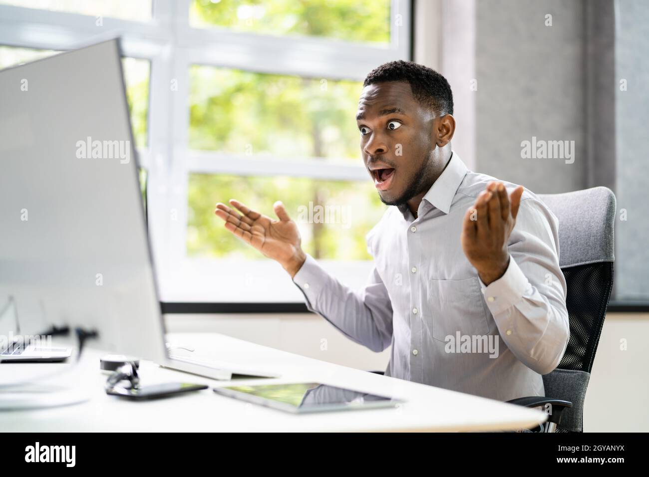 Shocked African Man With Ransomware On Office Computer Stock Photo