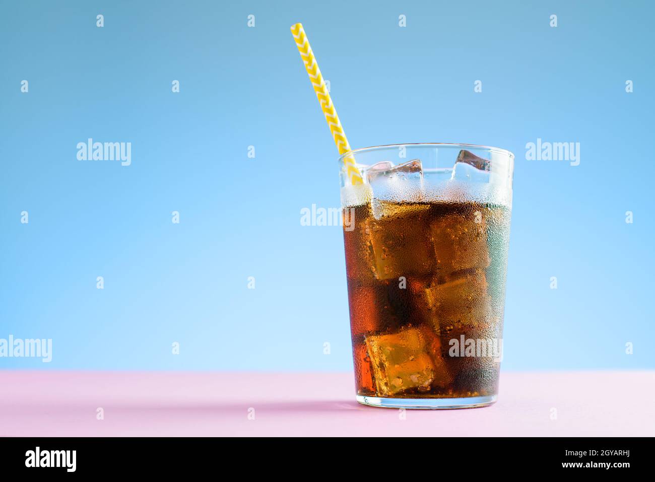 A glass of cola with ice cubes on blue and pink background Stock Photo ...