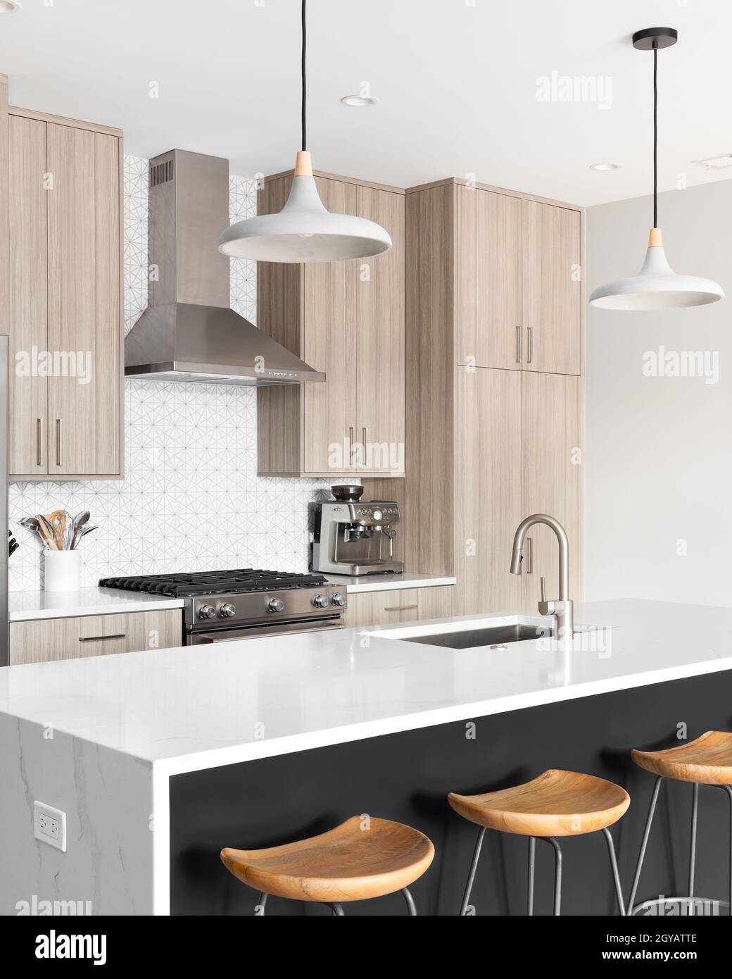 A beautiful, modern kitchen with a dark grey island with a white marble ...