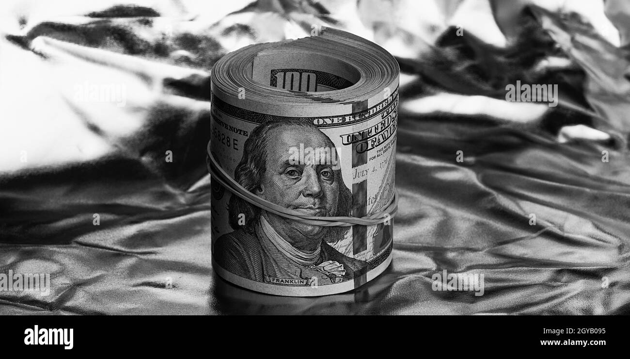 Roll of one hundred American dollars close-up black and white style. A big pile of cash dollars. One hundred dollar bills. Close-up, free space for ca Stock Photo