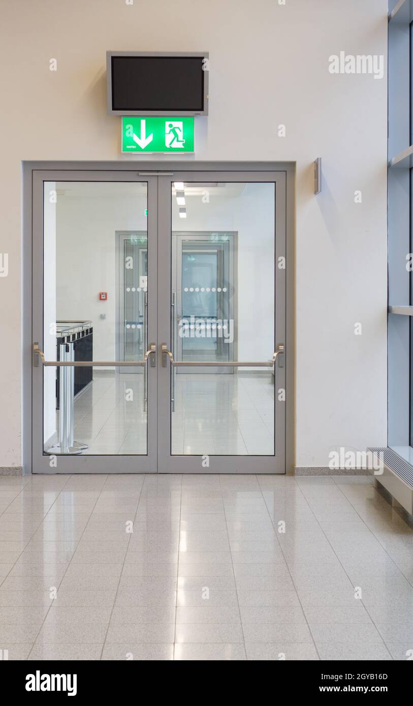 Double-leaf glass door with a green emergency exit lamp above it Stock Photo