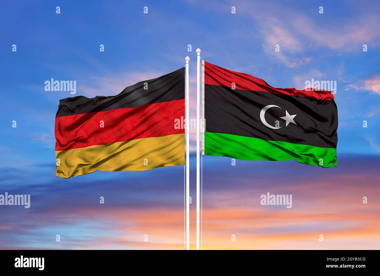 Libya and Germany flag waving in the wind against white cloudy blue sky together. Diplomacy concept, international relations Stock Photo