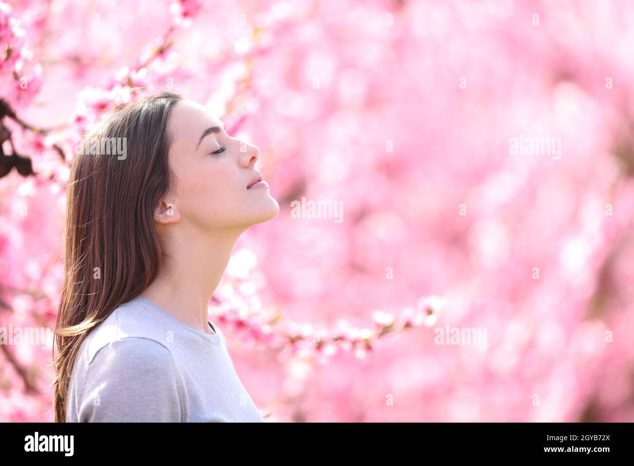 Side view portrait of a woman breathing and smelling scented flowers in ...