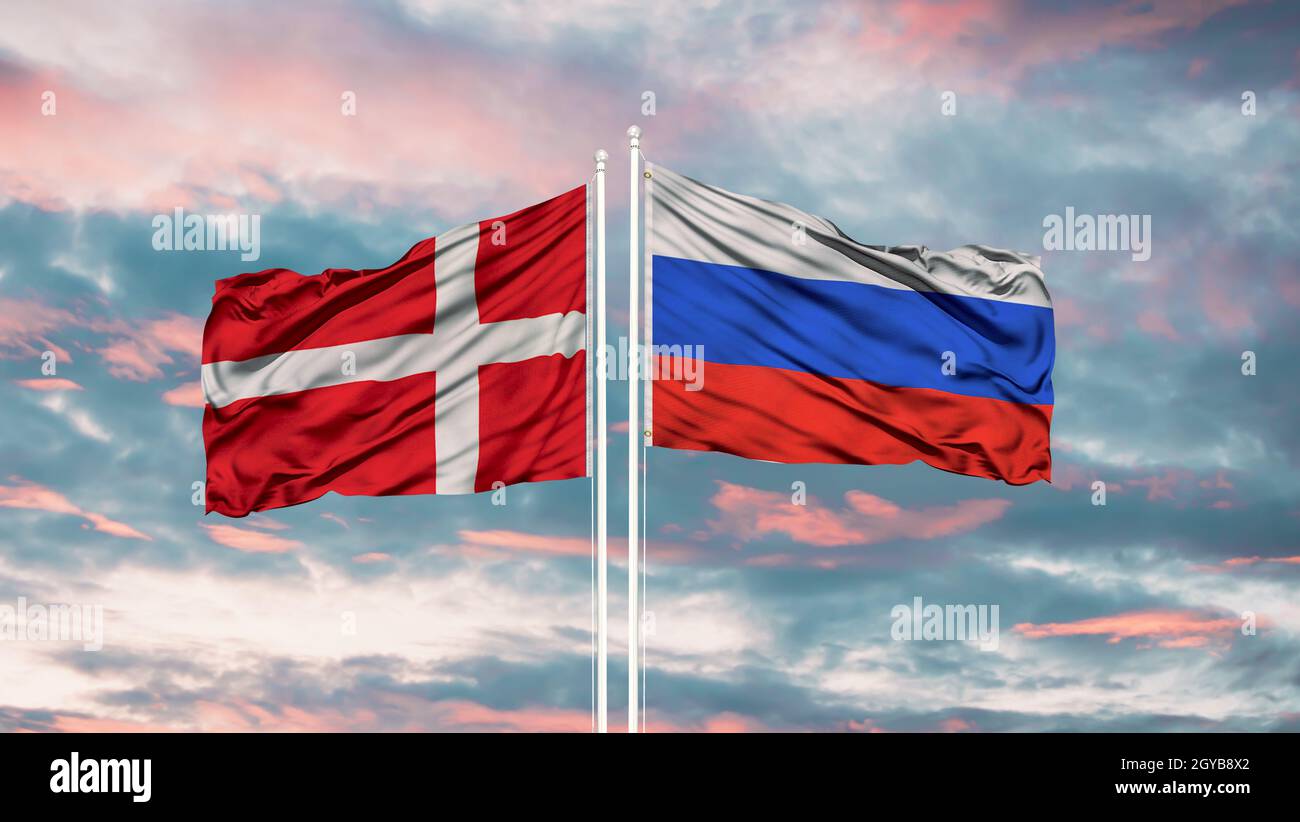 Russia and Denmark flag waving in the wind against white cloudy blue sky together. Diplomacy concept, international relations Stock Photo