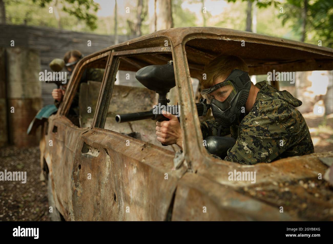 Male and famale warriors in camouflages and masks shooting with