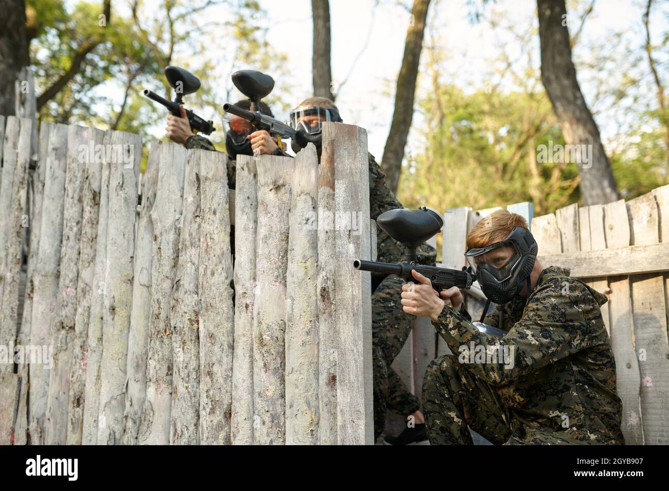 Paintball team shoots with guns, warriors in camouflages on playground