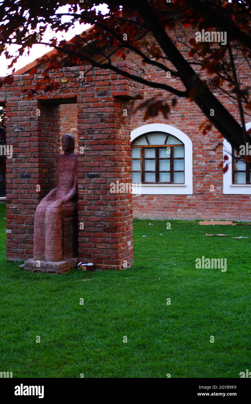 Surrealist sitting woman sculpture and brick wall  at the background outdoor Stock Photo