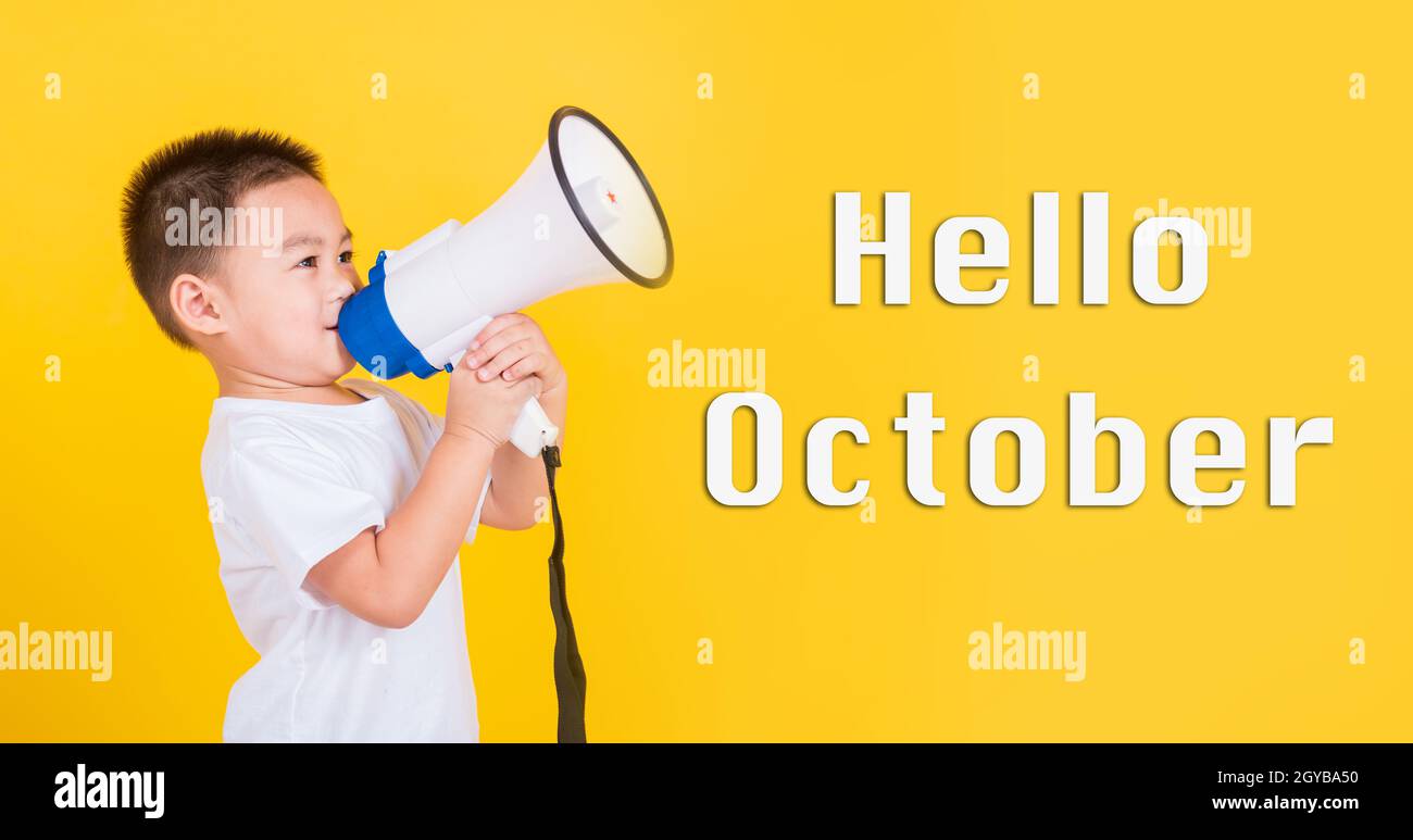 Hello October, Asian Thai happy cute little cheerful child boy holding and shouting or screaming through the megaphone her looking to side, studio sho Stock Photo