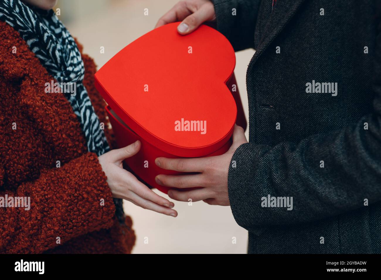 A guy gives his girlfriend giving heartshaped box close up in