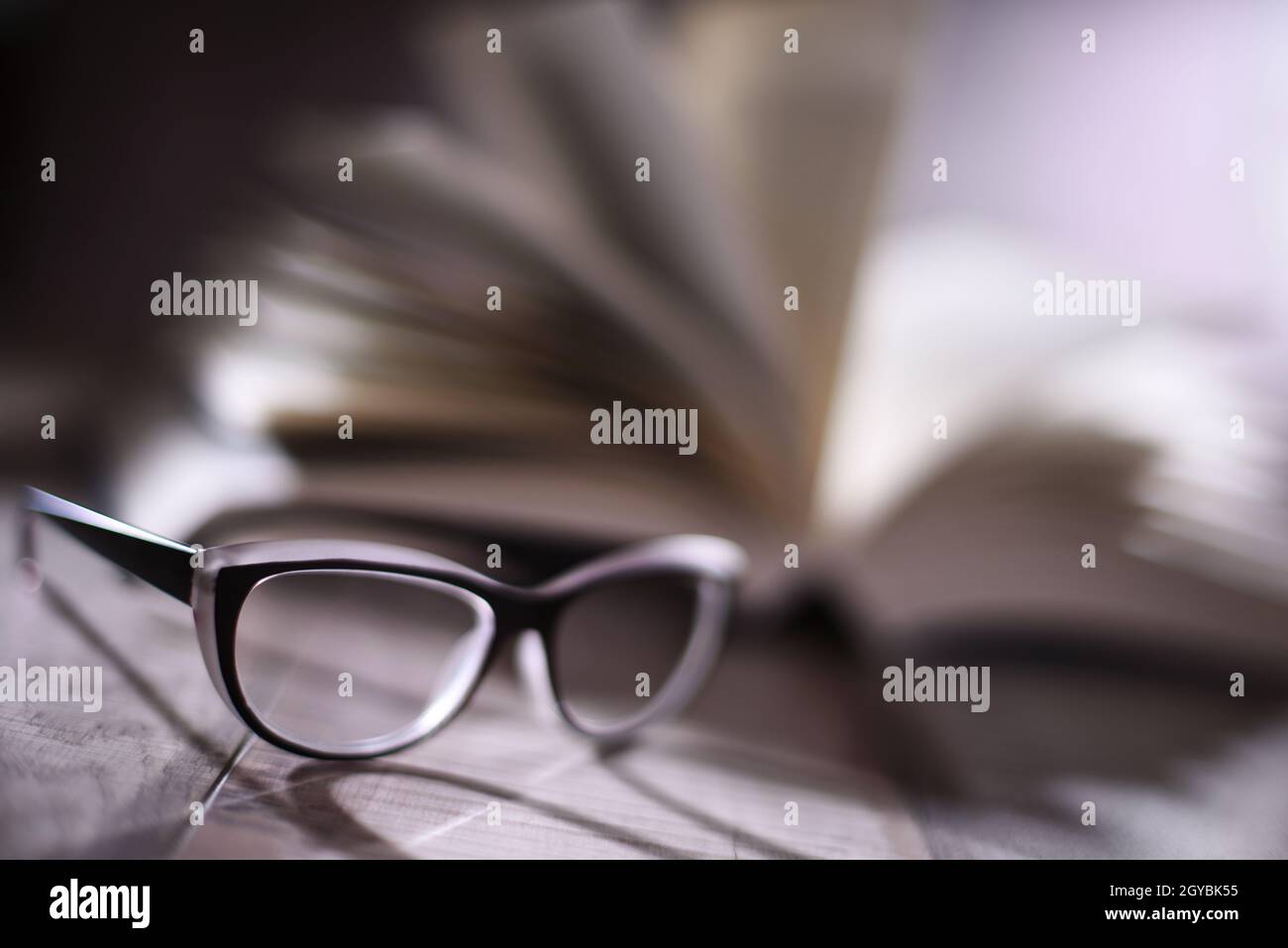 Composition with glasses and open book on the table. Stock Photo