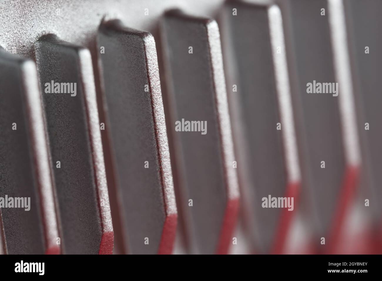 Aluminium or Aluminum heat sink cooling fins. Full frame super macro close up, showing metal detail and coarse finish. Red and silver color theme. Stock Photo