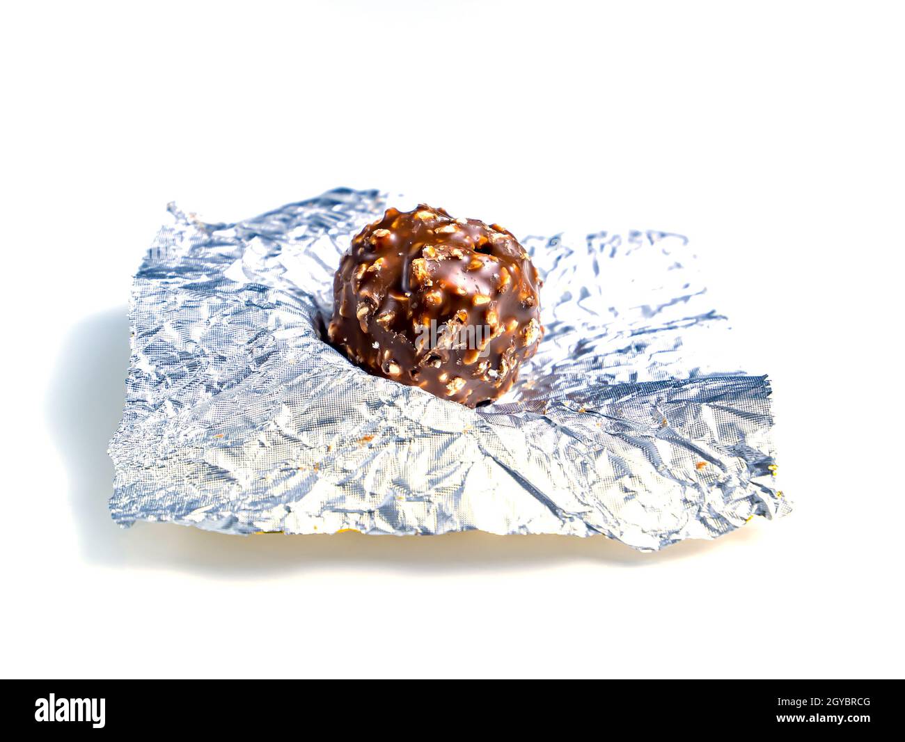 Round chocolate candies in a foil wrapper on a white background. Sweet