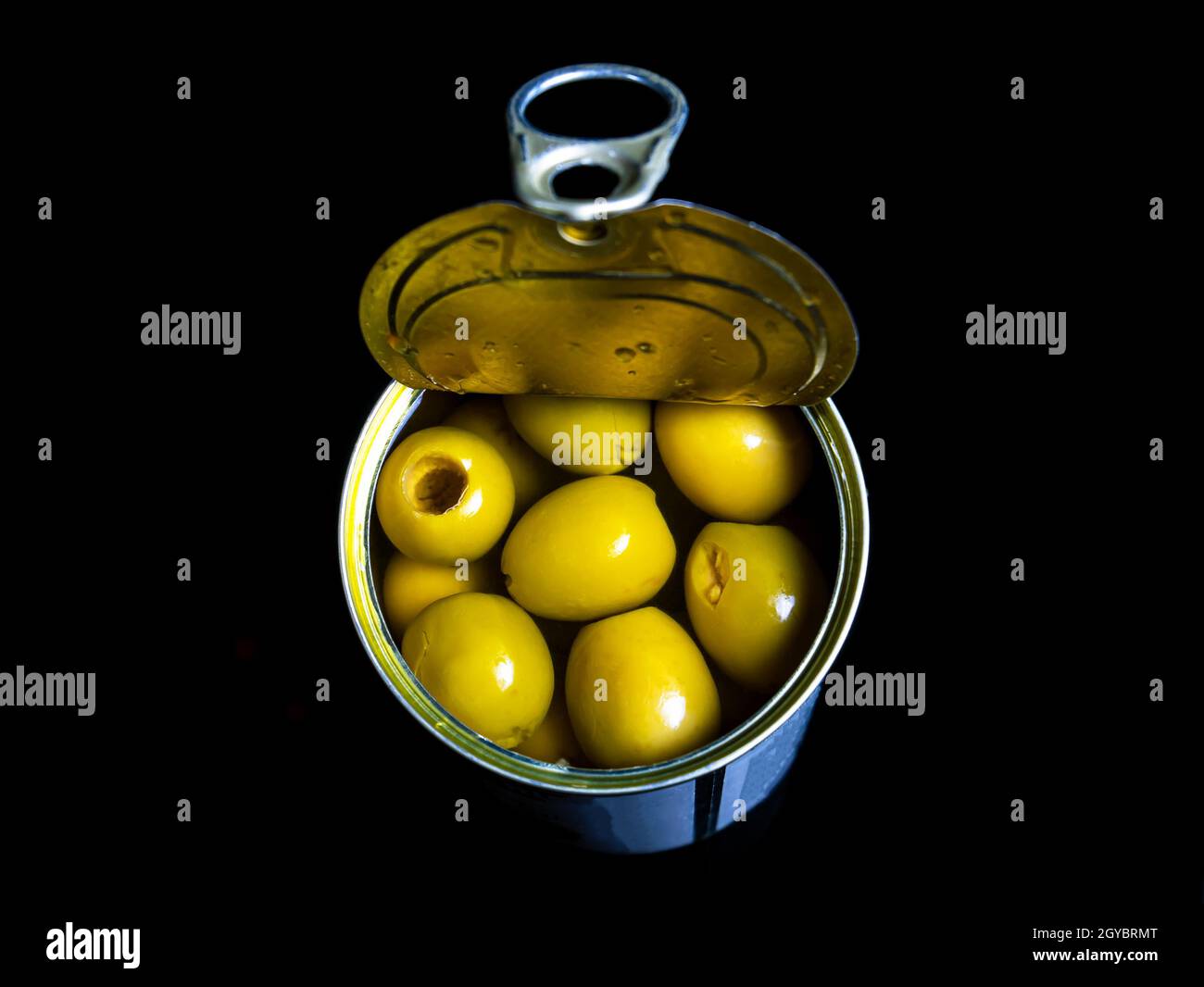 Green olives in a tin can on a black background. Green olive fruits. Olives berries. Olive fruits. Vegetables and fruits. Food photo. Canned food. Sna Stock Photo