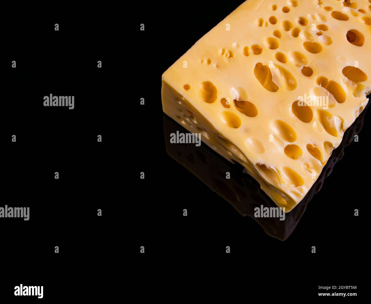 A piece of hard cheese on a black background. Hard cheeses. Milk product. Dairy products. Home kitchen. Food photo. Black background. Yellow. Healthy Stock Photo