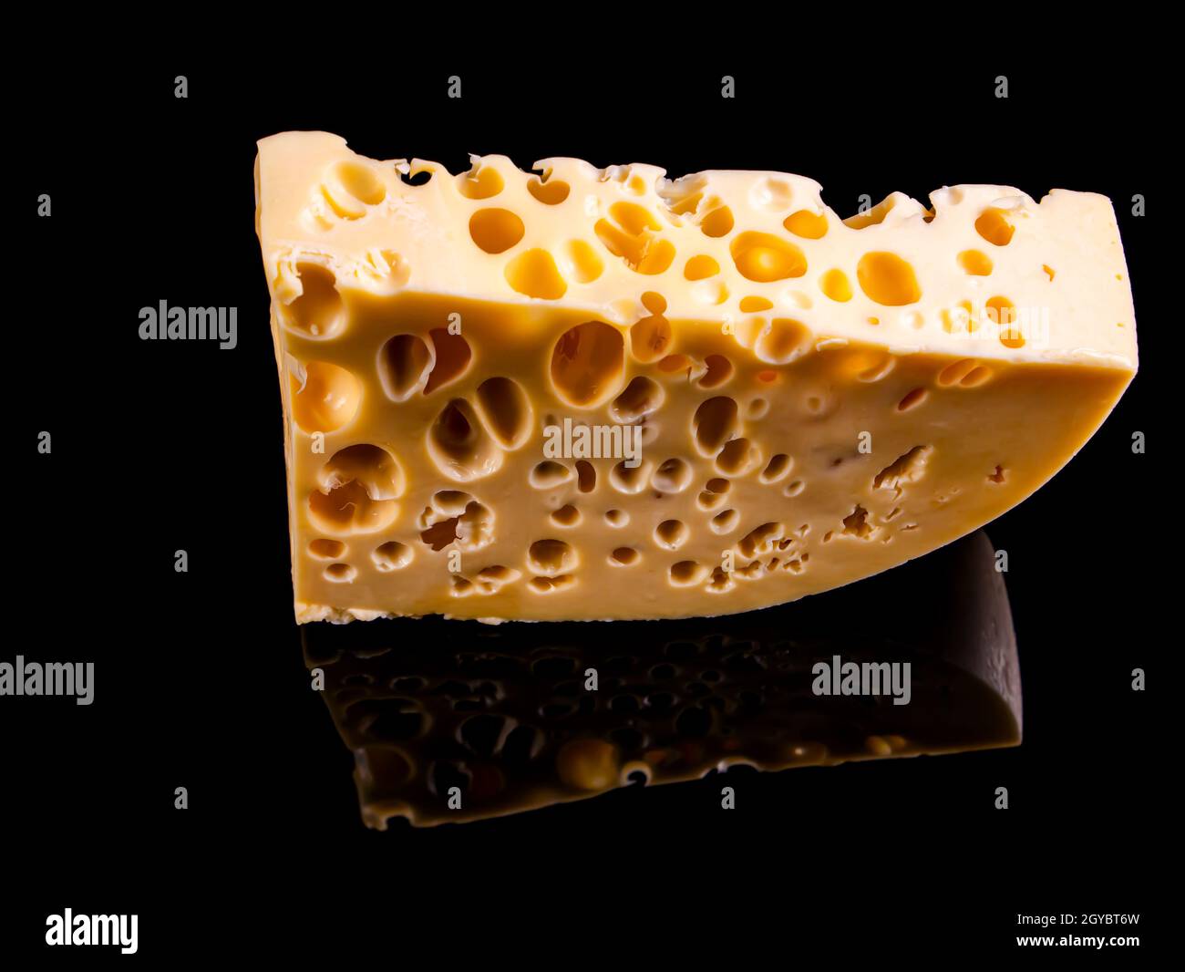 A piece of hard cheese on a black background. Hard cheeses. Milk product. Dairy products. Home kitchen. Food photo. Black background. Yellow. Healthy Stock Photo