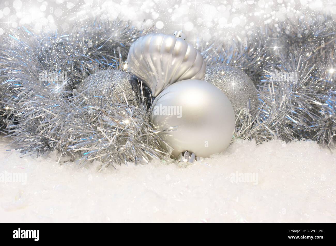 Silver Christmas baubles nestled in tinsel and snow Stock Photo - Alamy