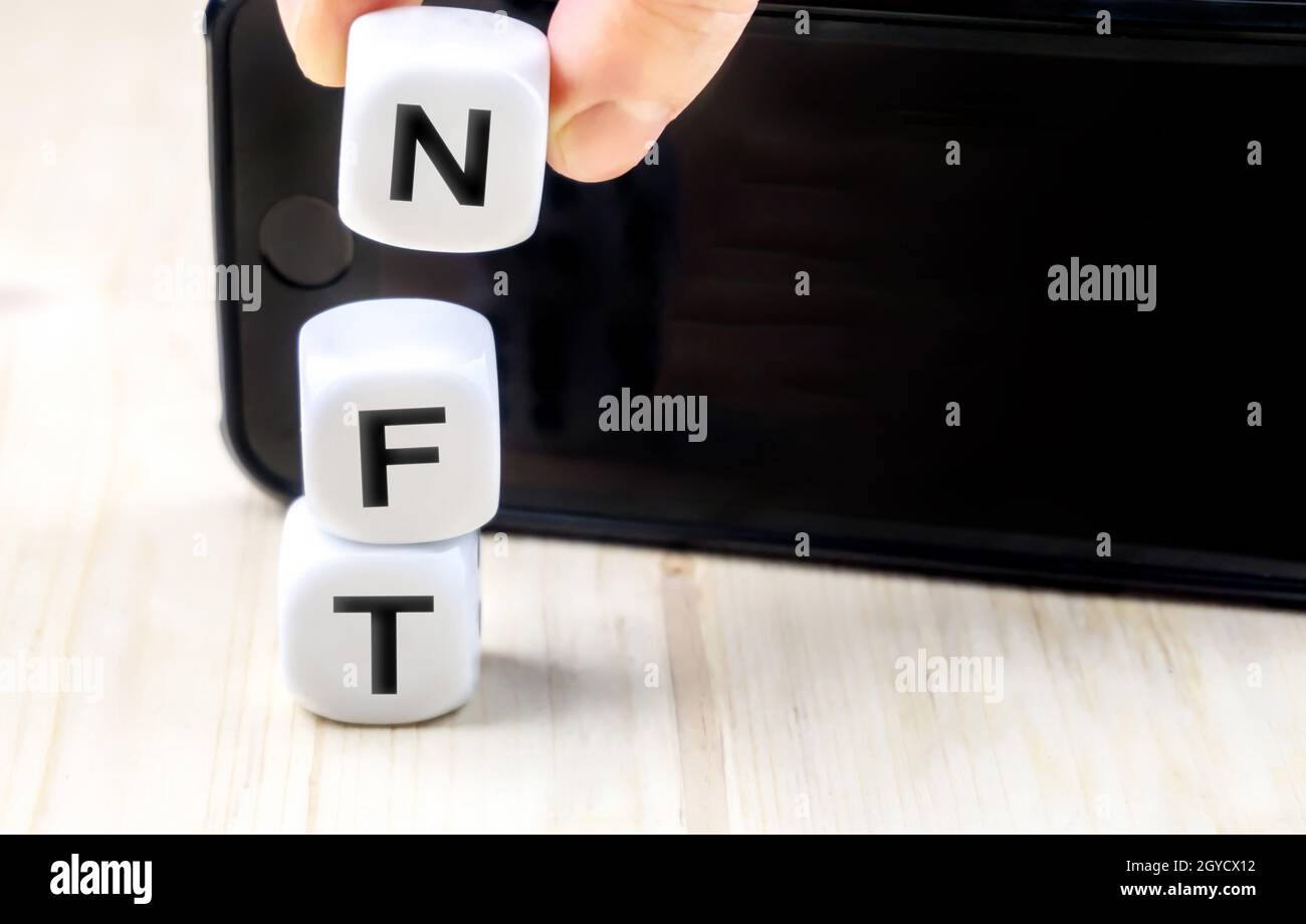 NFT or Non-Fungible token letters and dices, nft‘s are a blockchain market for art and collections smart phone with copy space Stock Photo
