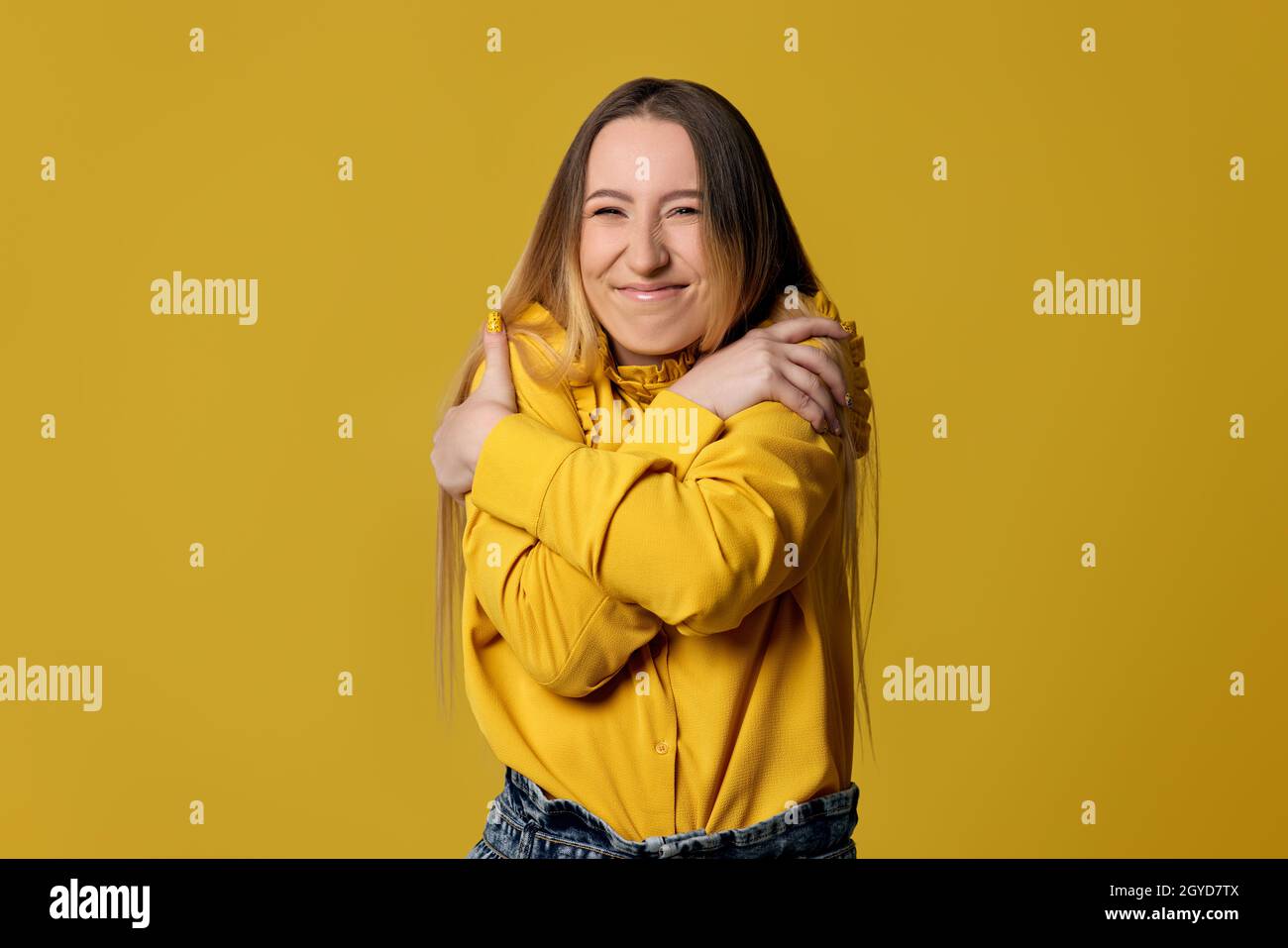 happy blonde woman hugging oneself positive on yellow background. Self love and self care Stock Photo