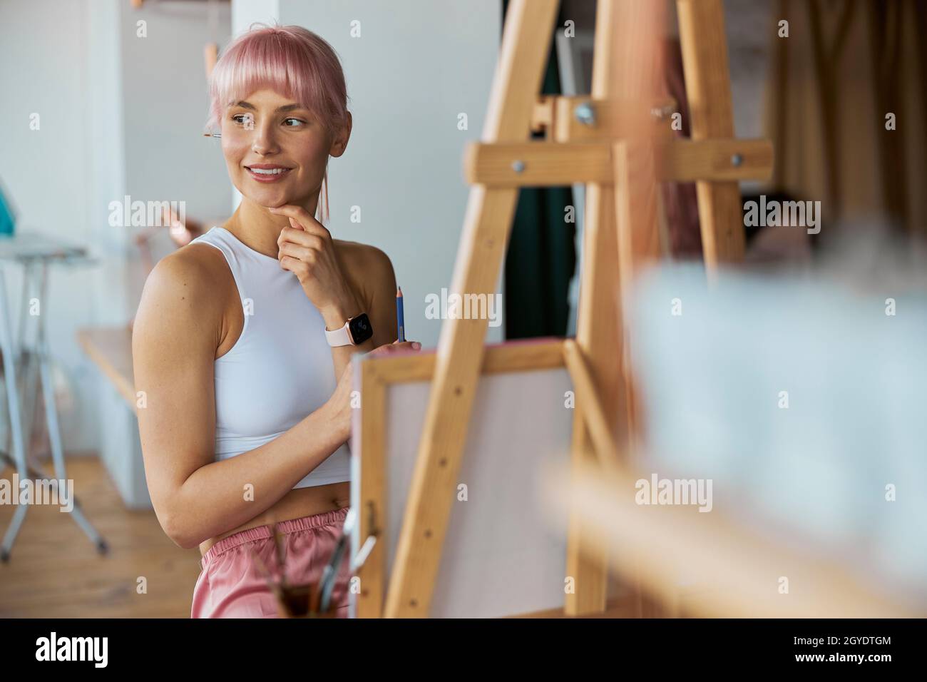 Elegant woman artist sits by easel with blank white canvas on at home ...