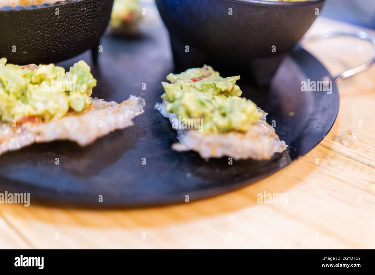 Pork rinds with guacamole and two bowls on traditional Mexican comal Stock Photo Alamy