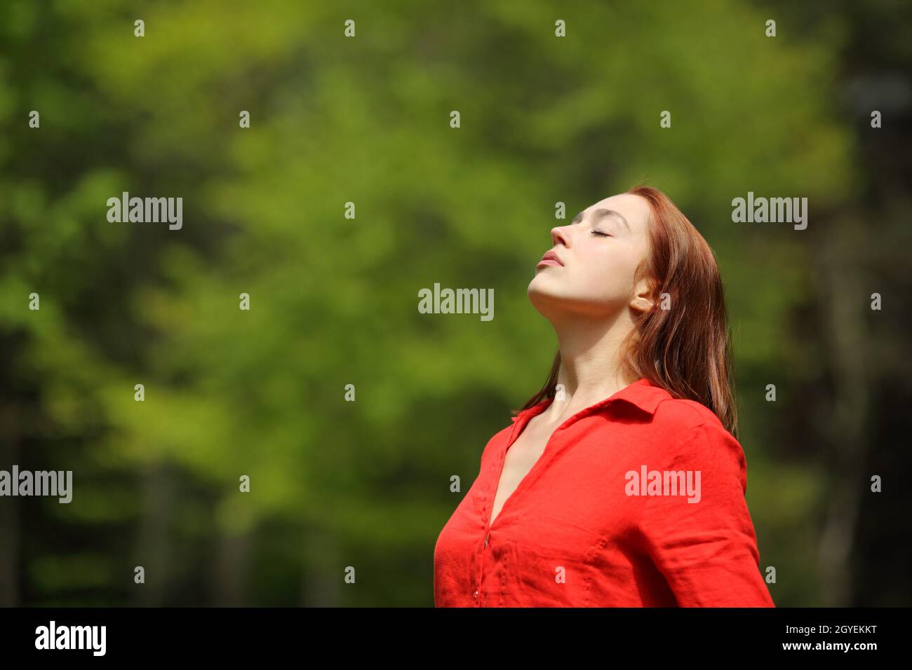 Relaxed woman in red breathing fresh air standing in a forest Stock ...