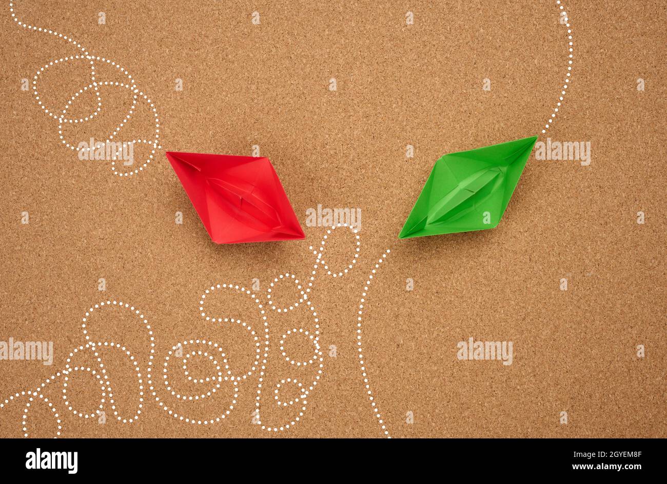two paper boats with different trajectory on a brown background. The concept of optimal problem solving, achieving goals in different ways, smart and Stock Photo