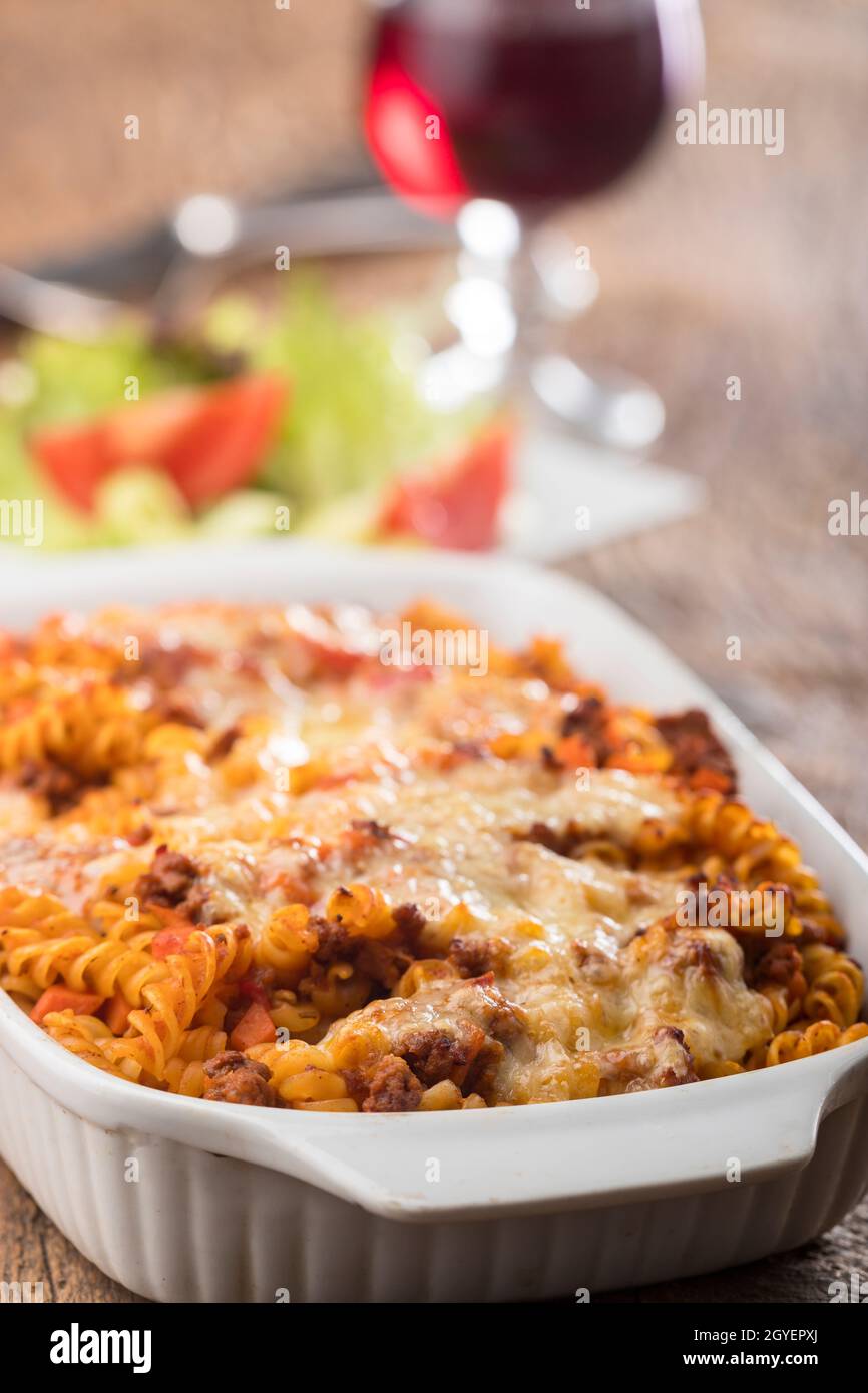 gratinated pasta with salad on wood Stock Photo