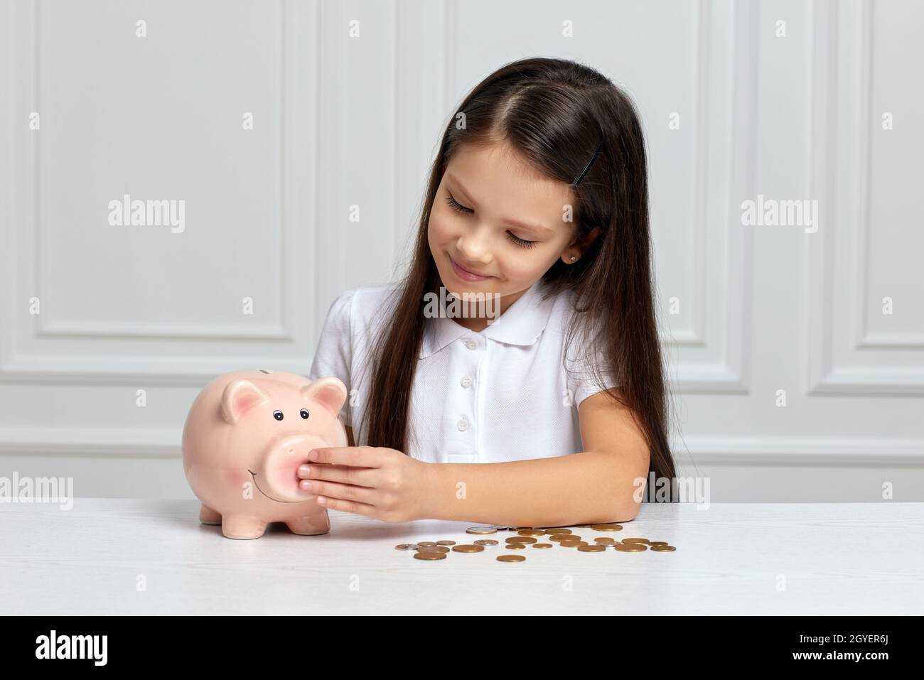 happy little child girl saving money for future in pink piggy bank ...
