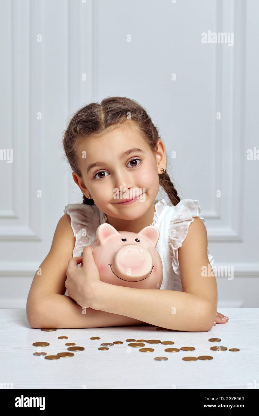 cute little child girl saving money for future in pink piggy bank Stock ...