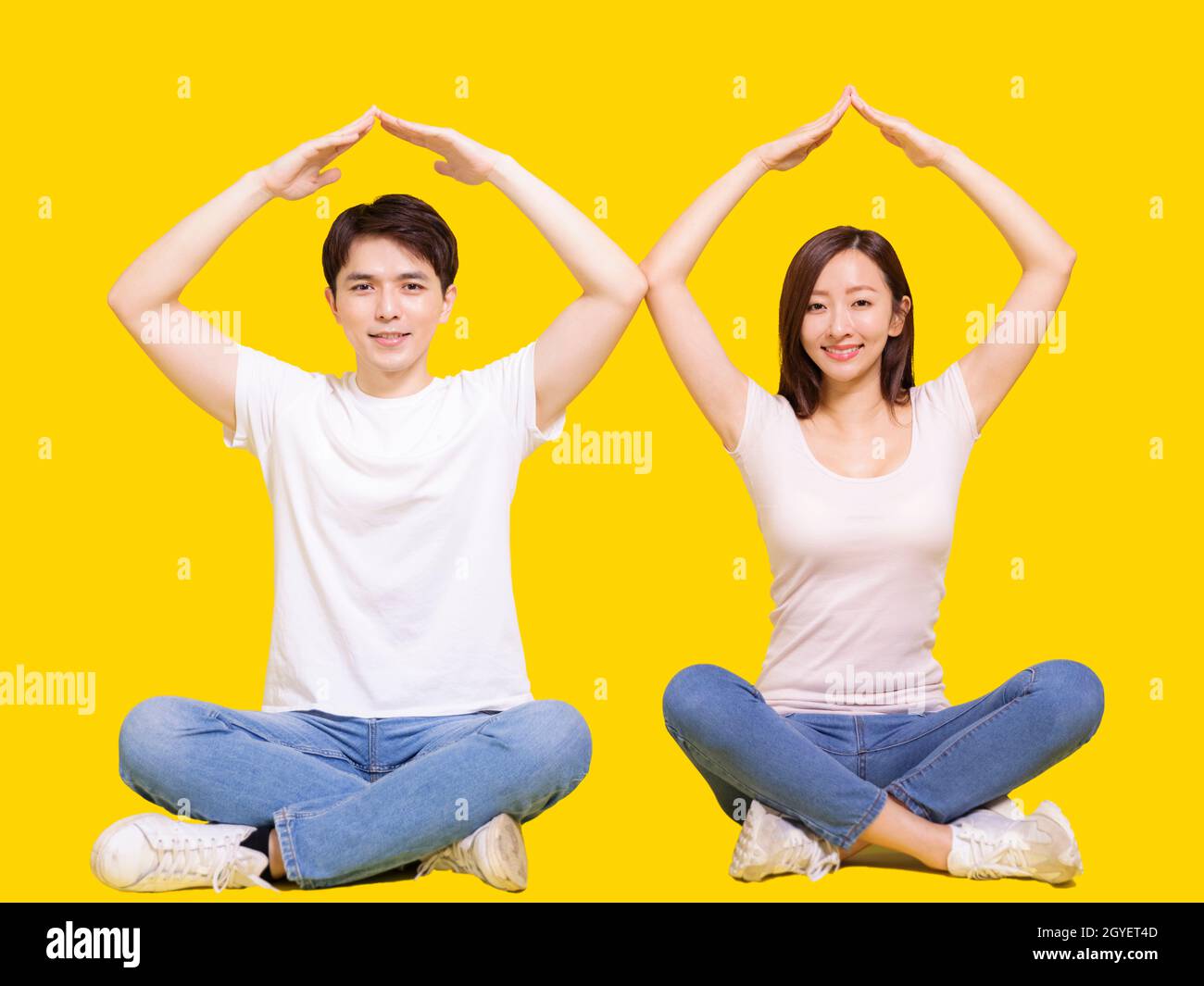Young happy couple with roof house hand gesture.Isolated on yellow background. Stock Photo