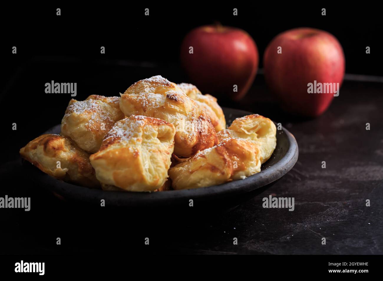 Homemade small apple turnovers in bowl on black background Stock Photo