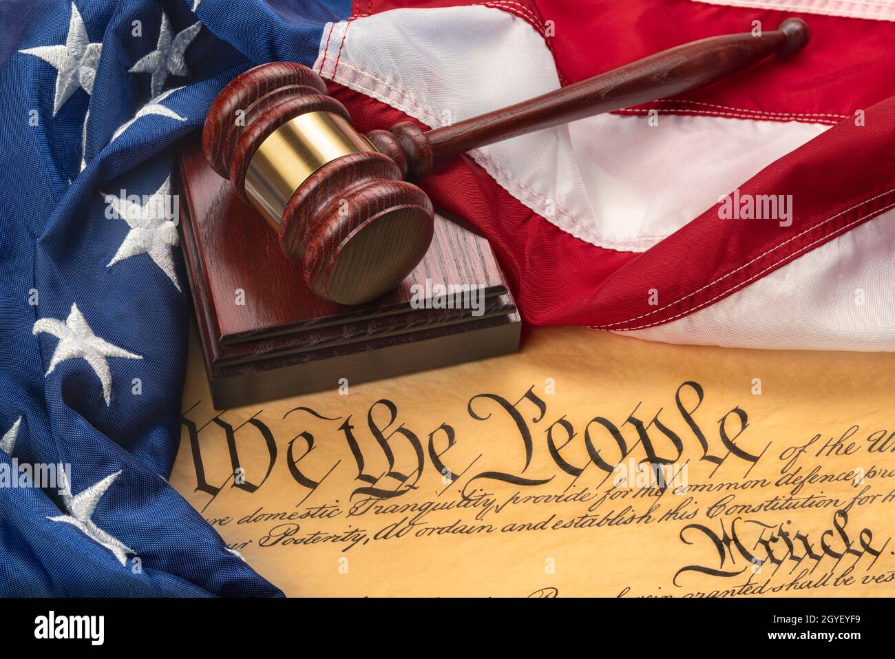 American flag draped around a judge's gavel block and the United States Constitution for use as a symbol of laws, freedom and separation of government Stock Photo