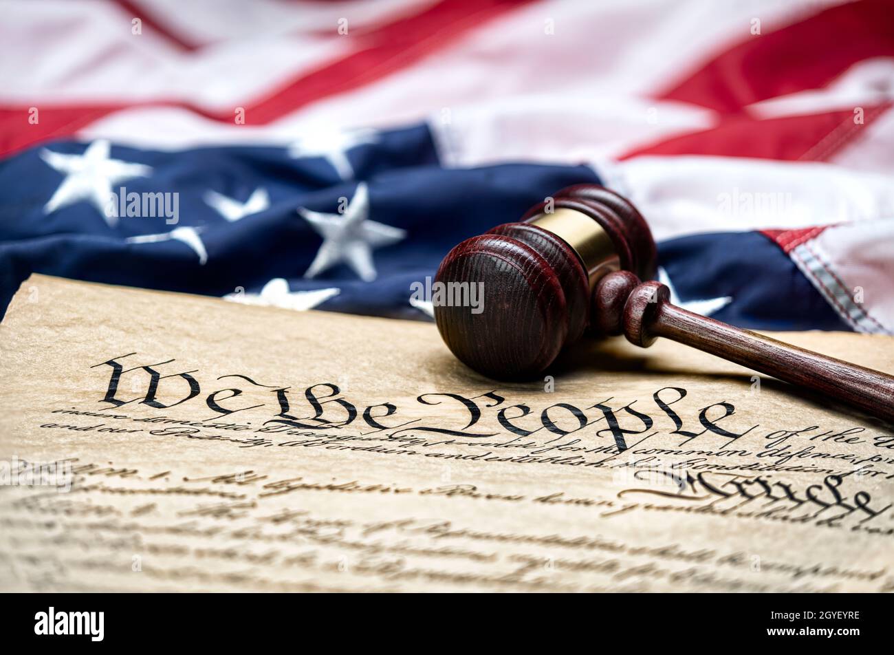 American flag draped around a judge's gavel block and the United States Constitution for use as a symbol of laws, freedom and separation of government Stock Photo