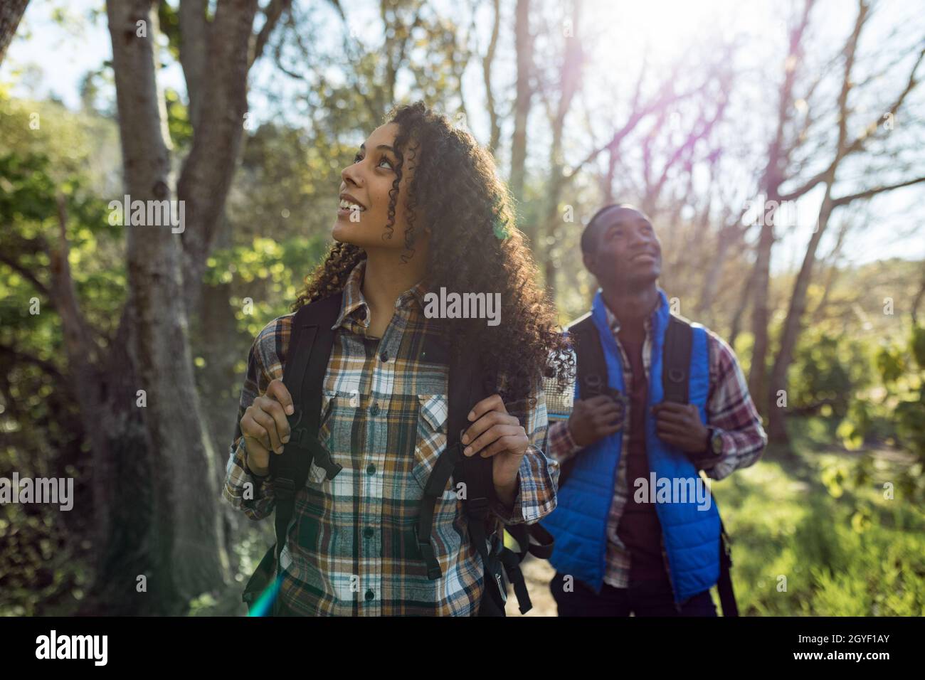 Happy diverse couple with backpacks hiking in countryside Stock Photo