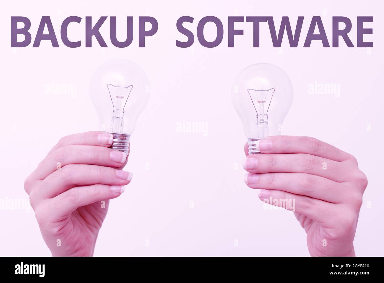 Writing displaying text Backup Software, Word for create extra exact copies of files or entire computers two Hands holding lamp showing or presenting Stock Photo