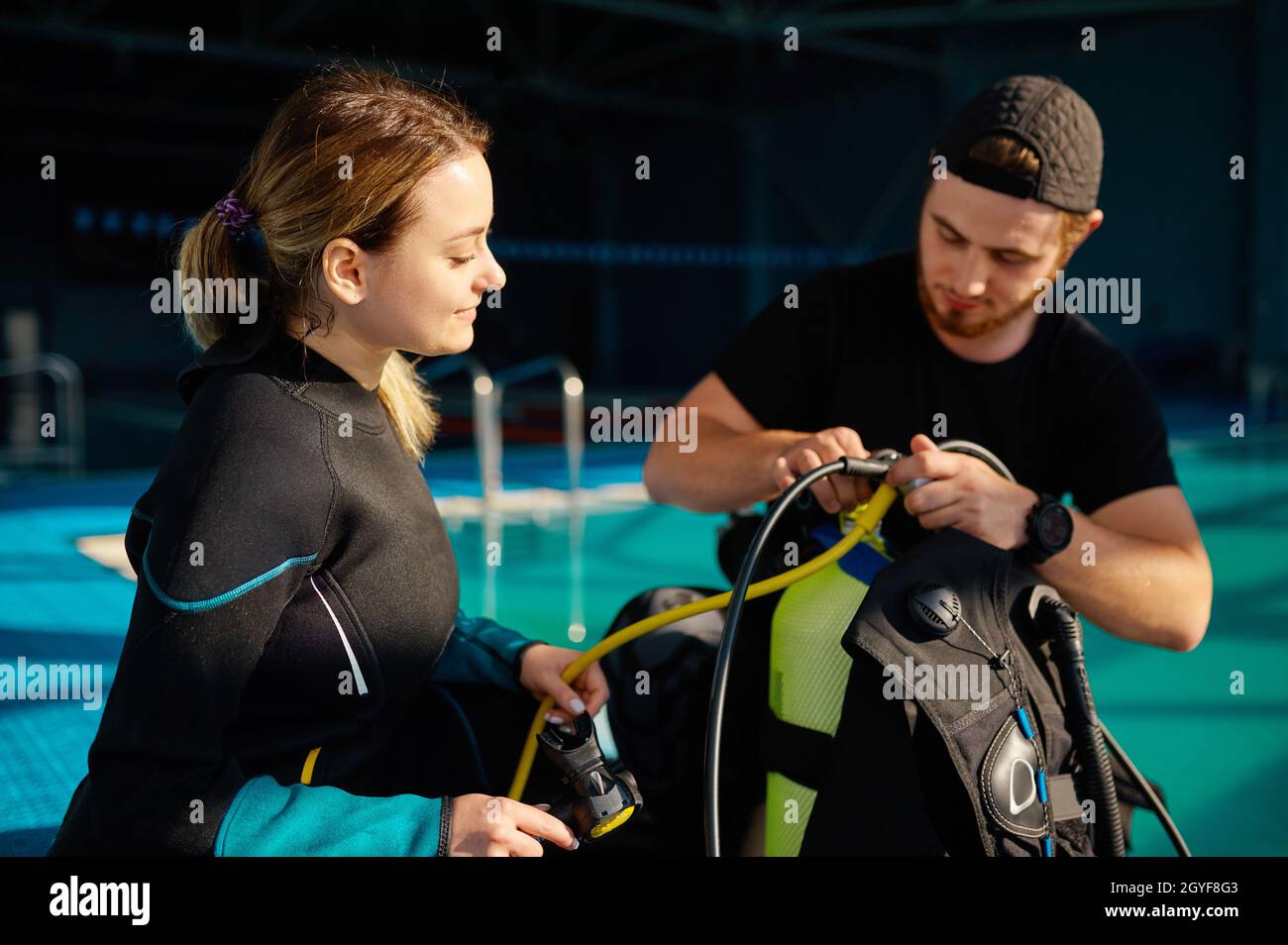 Male instructor in suit explains how scuba gear works, diving school