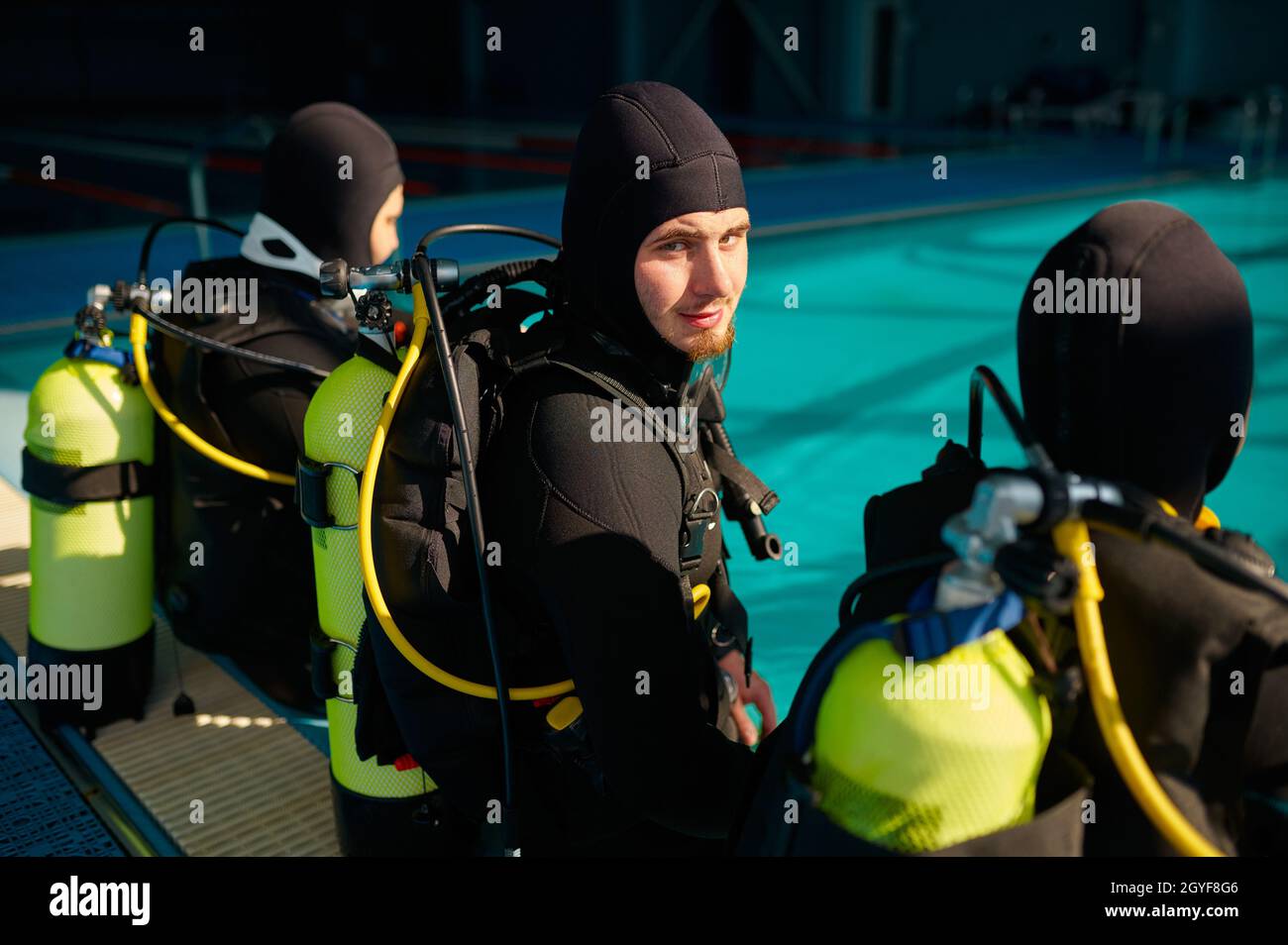 Divemaster and two divers in scuba gear preparing for the dive, diving