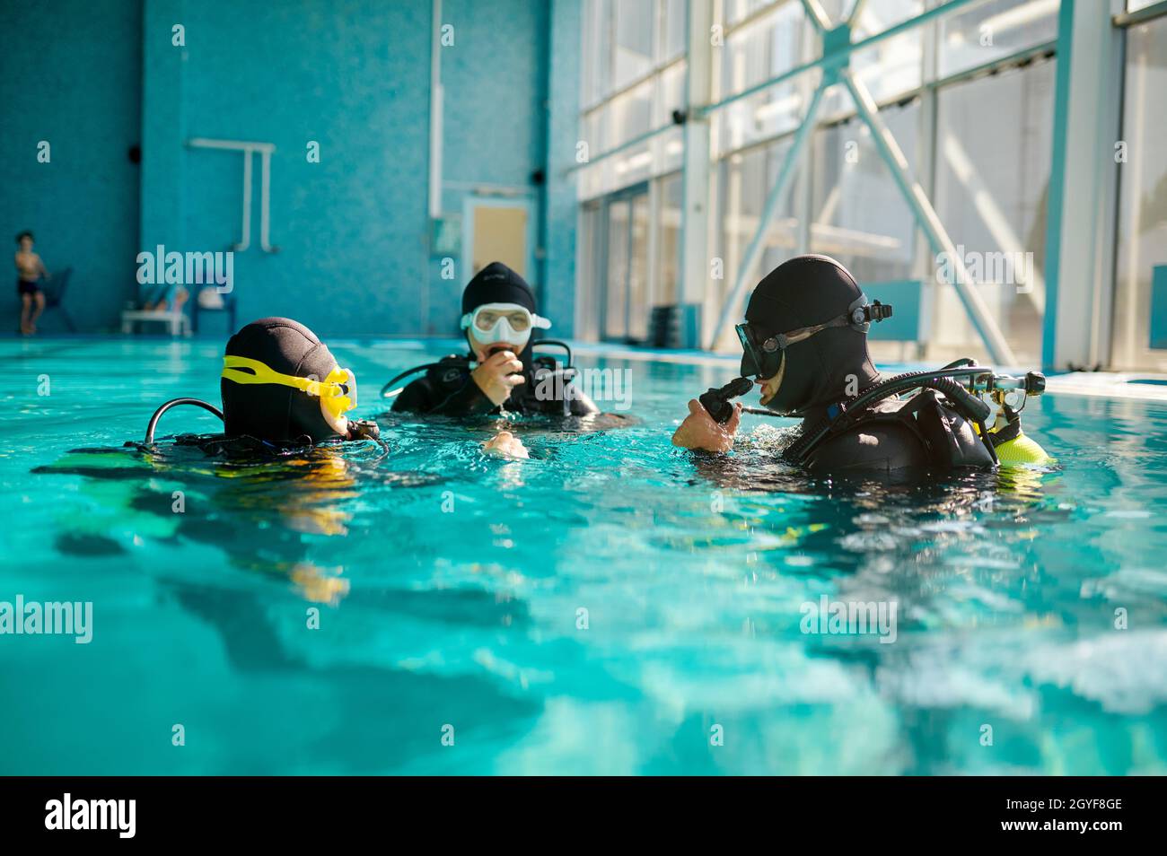 Divemaster and two divers in aqualungs, course in diving school