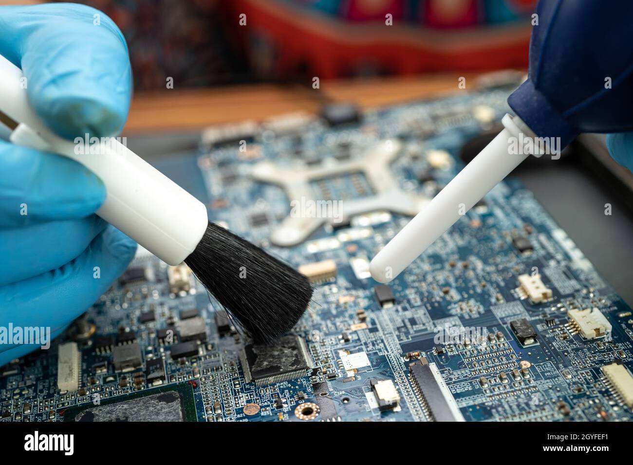 Technician use brush and air blower ball to clean dust in circuit board